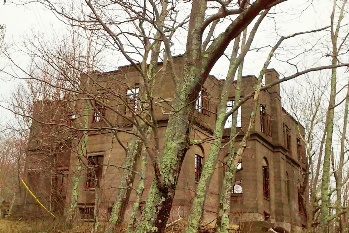 Crumbled concrete ruins of an abandoned hotel hidden deep in a foggy forest near Woodstock, New York, with vines and moss gro